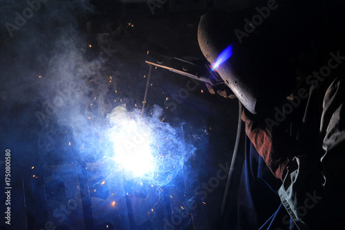 Industrial Welding Process with Bright Sparks and Blue Flame
