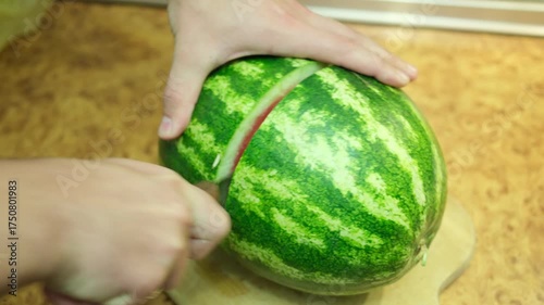 A man cuts a watermelon in half, showing its ripeness at the end.