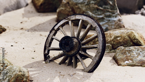 A rustic wagon wheel lies half buried in soft sand, surrounded by jagged rocks under a clear sky. This relic evokes a sense of history and natures embrace, blending serenity and antiquity.