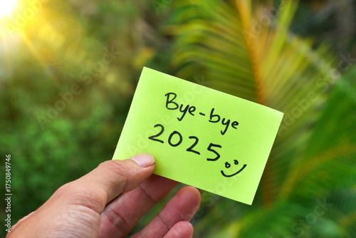 A hand holding a green sticky note with the message 
