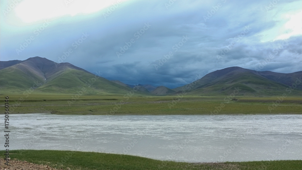 Naklejka premium Scenic landscape with river and mountains under cloudy sky