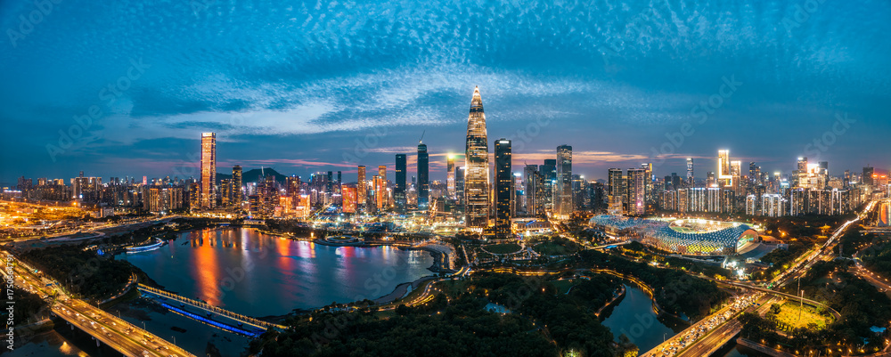 Fototapeta premium Panoramic view of the modern city skyline with illuminated skyscrapers across the bay at night in Shenzhen, Guangdong province.