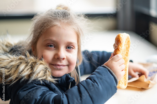 Photography girl eats a puff pastry with a delicious filling in a cafe