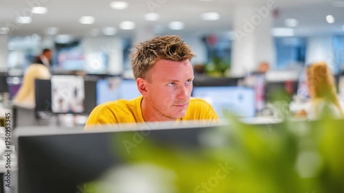 Focused Professional in Modern Office Environment: A Dedicated Worker Engaged in Computer Task Amidst a Dynamic Workplace Atmosphere