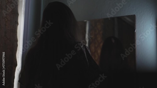 Dark cinematic Halloween shot featuring a possessed woman staring into an antique mirror in a haunted setting. Perfect for horror intros, thriller trailers, or supernatural themed