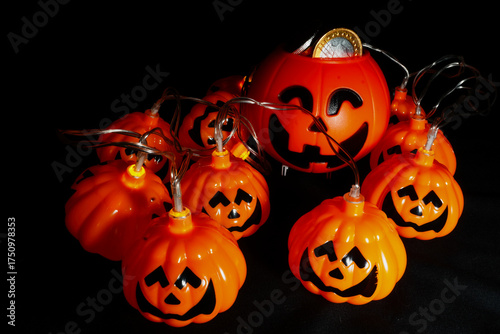 Decorative plastic pumpkins with smiling faces illuminated by string lights, creating a fun and festive Halloween atmosphere perfect for seasonal decoration and celebration themes