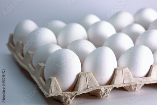 Close Up Angled View Of Fresh White Chicken Eggs In A Recycled Paper Cardboard Carton On A White Background. Grocery And Food Concept.