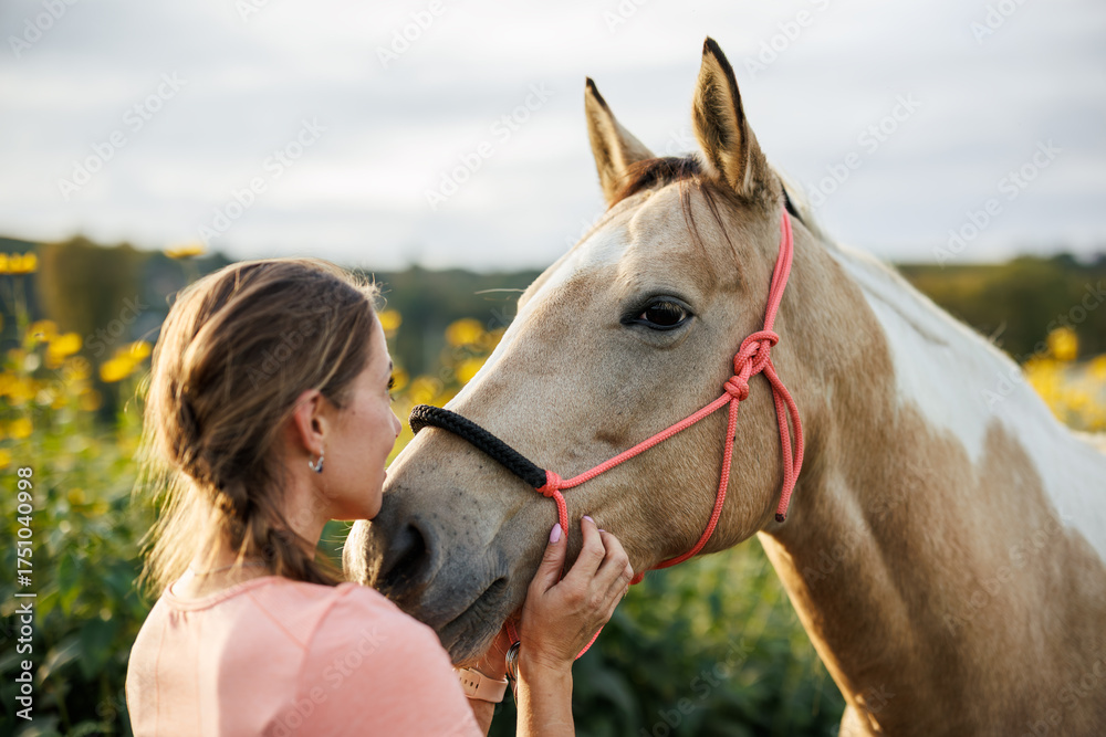 Obraz premium Affectionate moment between woman and her horse. Female rancher standing close to her paint horse expressing trust and friendship