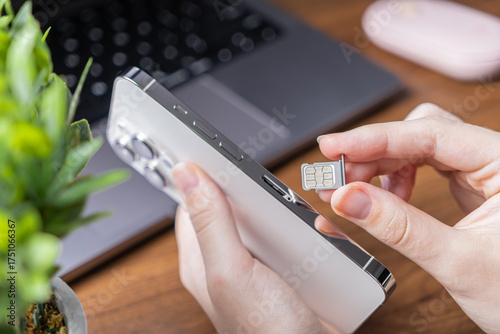 Foto Person's hand holds a sleek smartphone, preparing to insert a nano SIM card, rep