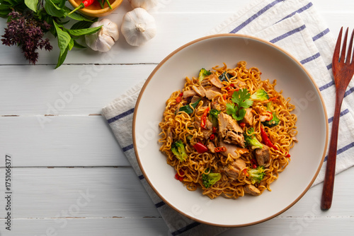 Photos Spicy stir fried instant noodle with canned tuna fish broccoli and thai basil leaves in white plate