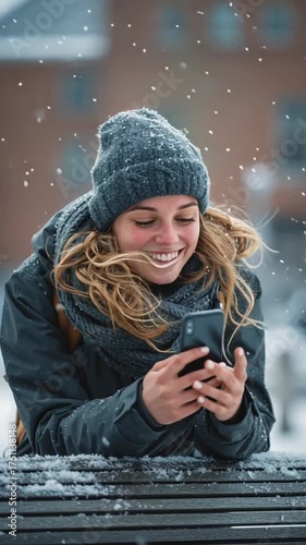 Female college student using her smartphone while on a university campus during a snowy winter day