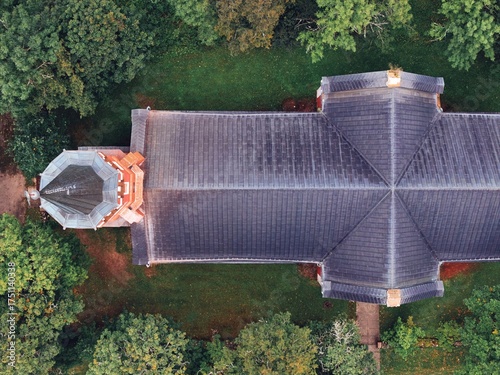 Halliste, Estonia September 25, 2025: Aerial view showing a religious building with a dark tiled roof and an octagonal tower, nestled in a vibrant green forest