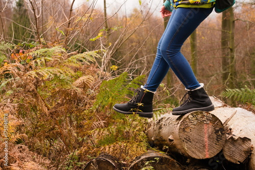 Walking on fallen tree trunk in autumn forest with black boots