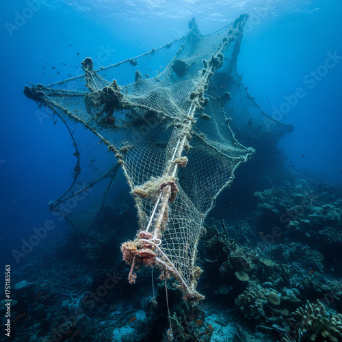 Underwater view of a large fishing net resting on a vibrant coral reef ecosystem
