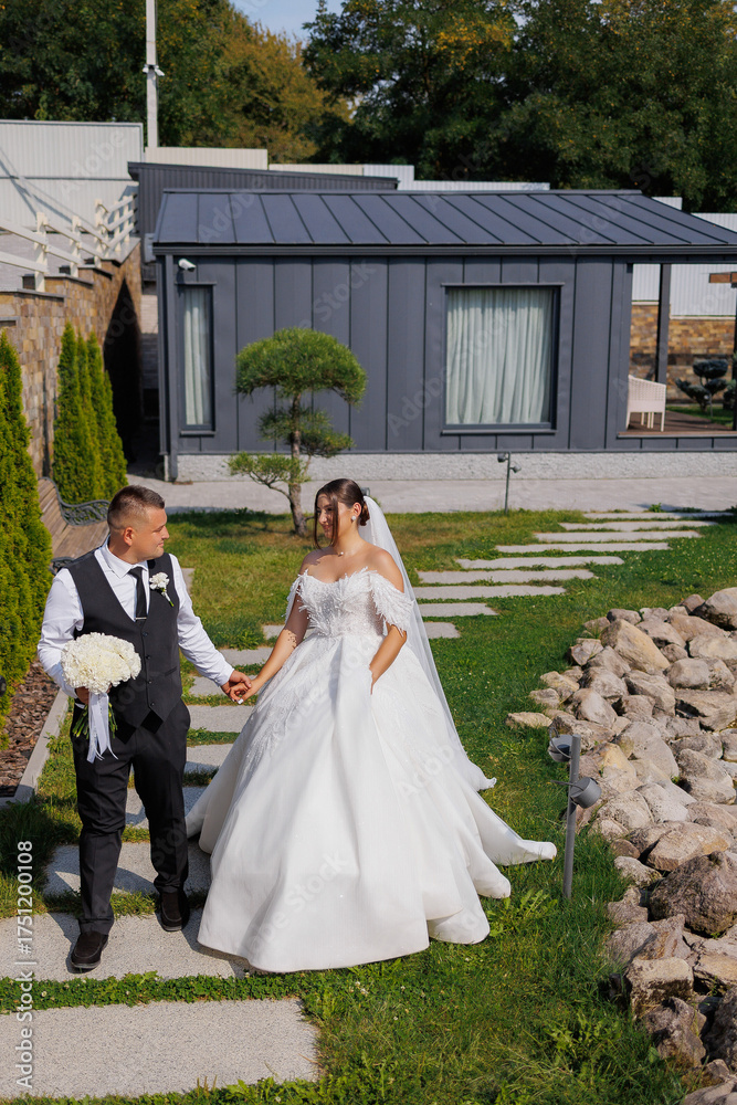 Fototapeta premium Couple enjoys outdoor wedding celebration near modern house in bright daylight