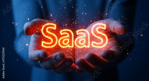 Hands holding glowing saas text with sparks and light effects
