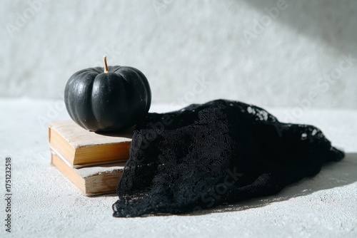 Black Pumpkin and Lace Cloth on Wooden Books in Soft Light