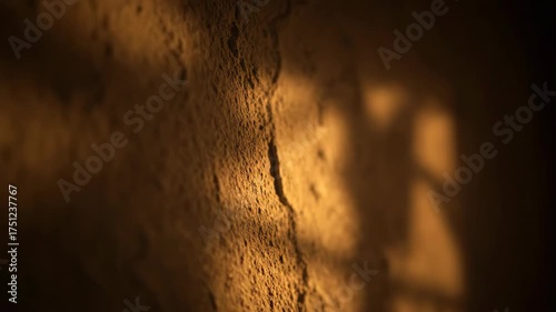 Warm light illuminating a textured wall with shadows, close up