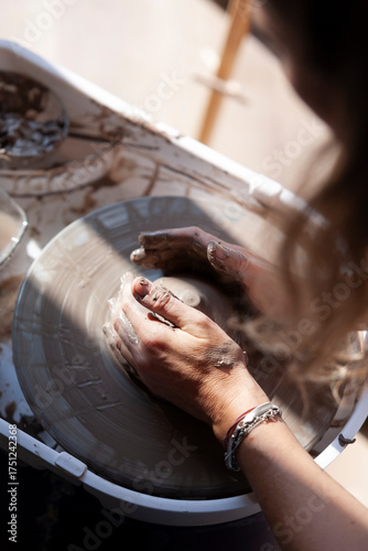Overhead view of woman’s hands shaping clay on pottery wheel