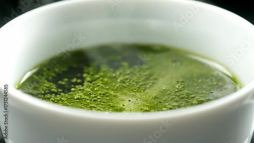 Close-up of a cup with a green, steaming drink in a white cup.