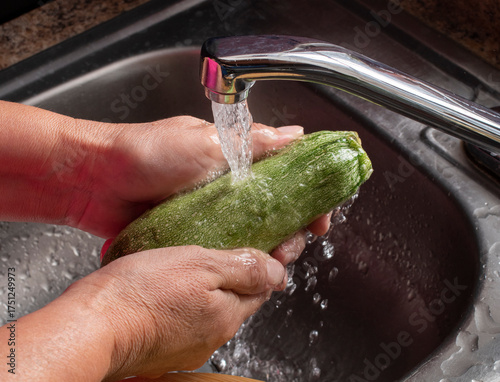 Manipulacion de alimentos, manejo de comida en la cocina ,manos lavando una calabacita con agua de la llave