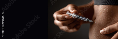 A close up of a Black woman injecting herself into her stomach with a syringe. The medication is used to treat diabetes, lose weight, and manage illnesses. Banner with space for text.