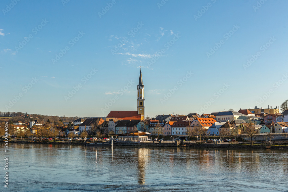 Fototapeta premium Panoramic view of Vilshofen an der Donau with church tower and colorful houses reflected in the river