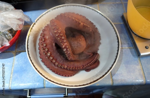 A hot, steaming octopus on a plate ready to be cut and prepared for a salad.