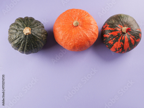 Three colorful pumpkins on purple background