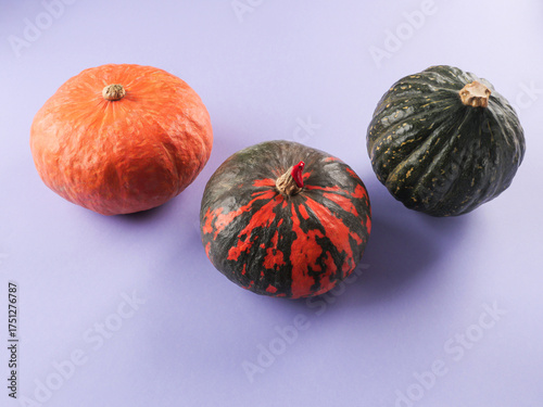 Three colorful pumpkins on purple background