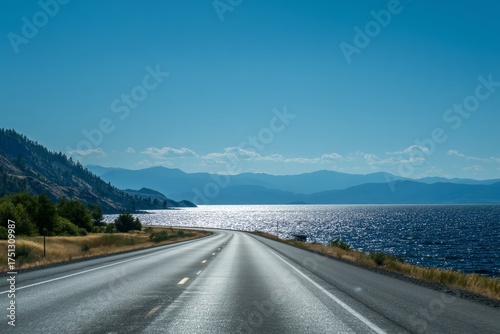 Scenic Highway Along the Shimmering Lake Under a Clear Blue Sky in the Aftern...