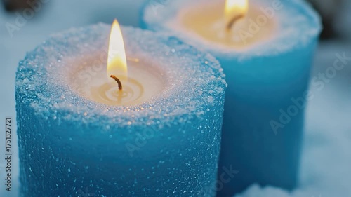 A winter scene with two blue candles lit against a snowy backdrop