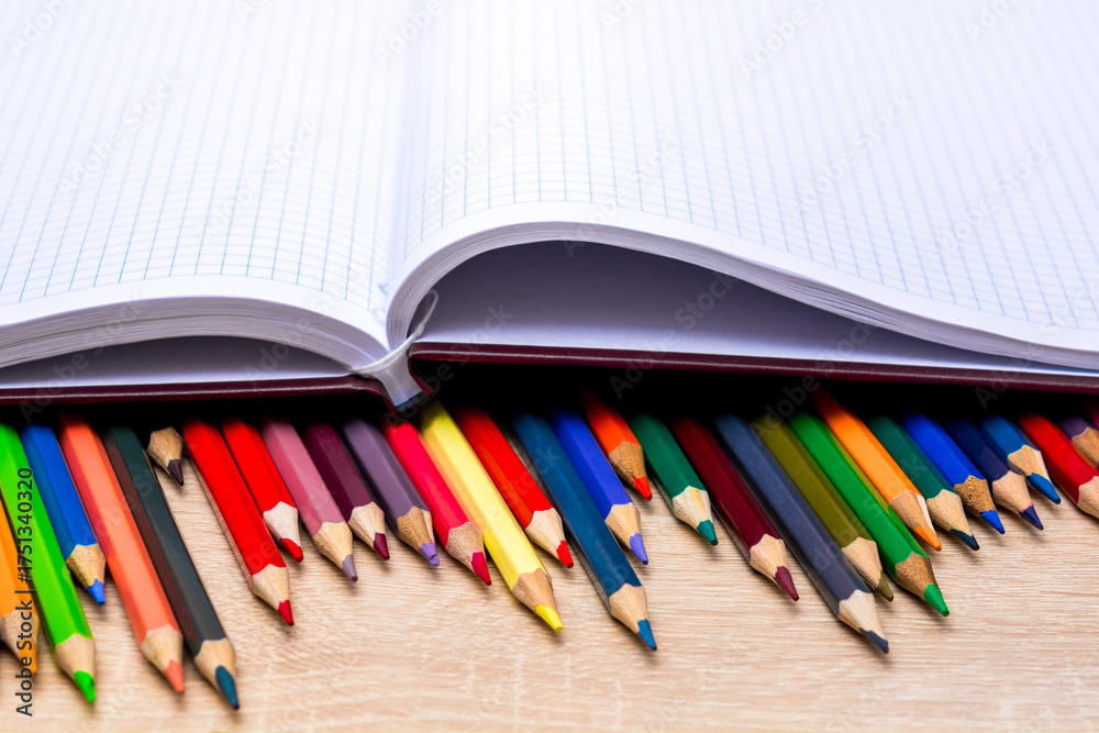 Obraz premium Colored pencils and a notebook