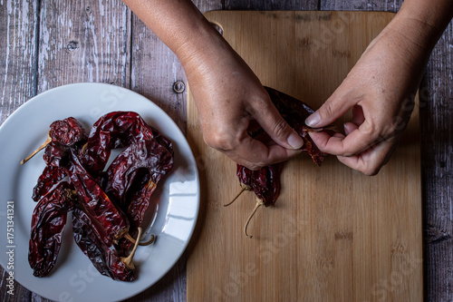 Manipulacion de alimentos, manejo de comida en la cocina, manos quitandole las semillas a unos chiles secos guajillo