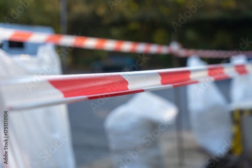 Photography Red and white striped warning tape restricting access outdoors on a blurred stre