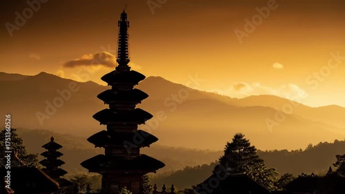 Silhouetted tiered pagoda at sunset, mountains in hazy golden light