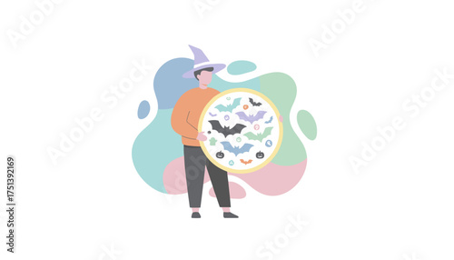 Person in a witch hat holding a festive Halloween display with bats pumpkins and ghosts
