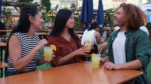 Three friends sharing drinks and laughter at an open air bar