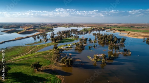 Aerial view of flooded fields and trees under a blue sky with scattered clouds
