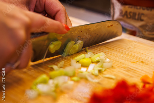 Chef expertly slicing fresh leeks on a wooden cutting board for a gourmet meal