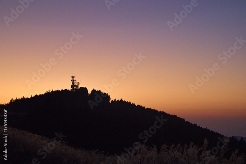 夕焼け空と電波塔が立つ秋の山並み