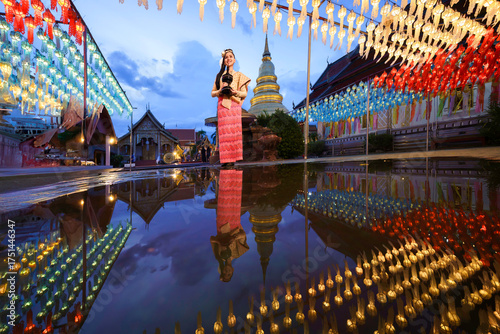 Fotografía Pretty Asian woman in Thai traditional costume in the Hundred Thousand Lantern Festival or Yi Peng Festival for worship at Phra That Hariphunchai temple in Lamphun, Thailand