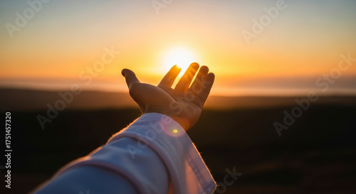 A Hand Reaching Towards the Warm Golden Sunrise in a Peaceful Landscape