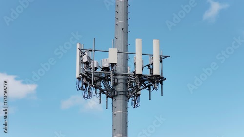 Aerial orbit view of mobile phone cell tower against blue sky with white clouds, low angle view