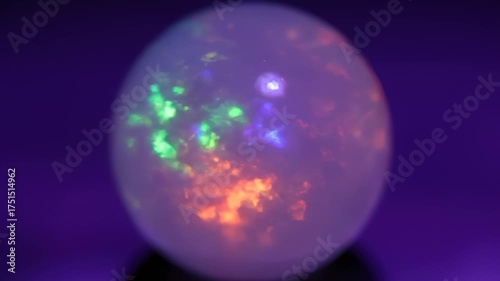 Close Up of Glowing Crystal Ball With Fire Opal Inclusions on Dark Violet Surface