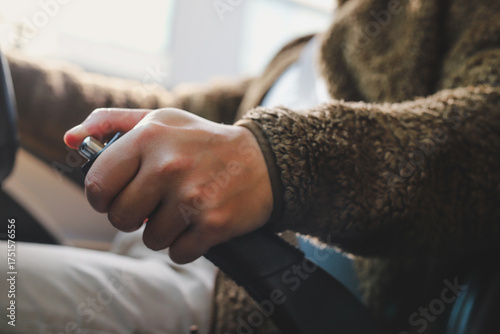 Close-up of a man holding the handbrake while sitting in a car.