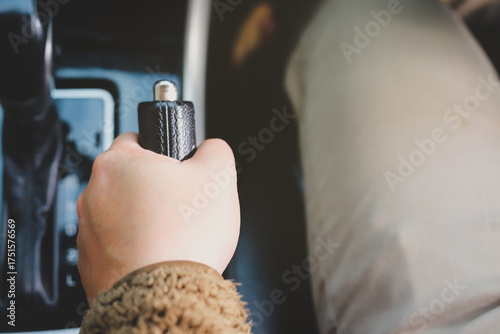Close-up of a man holding the handbrake while sitting in a car.