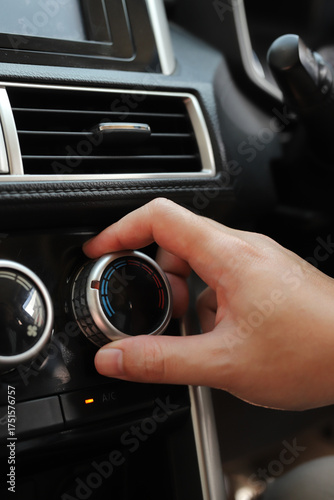 close up hand air conditioning and center console of car for temperature.