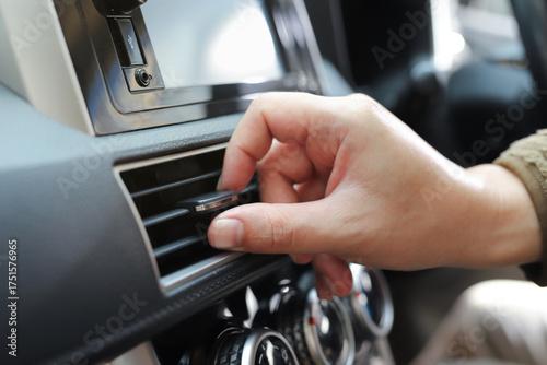 close up hand air conditioning and center console of car for temperature.