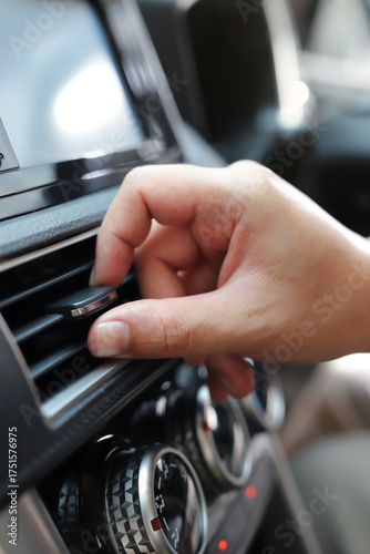 close up hand air conditioning and center console of car for temperature.